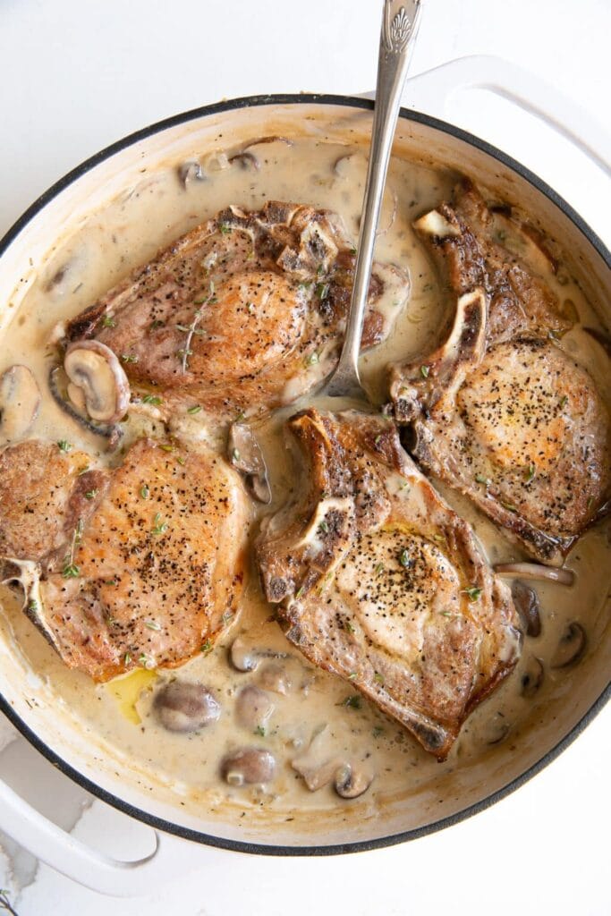 Creamy smothered pork chops in a pot.