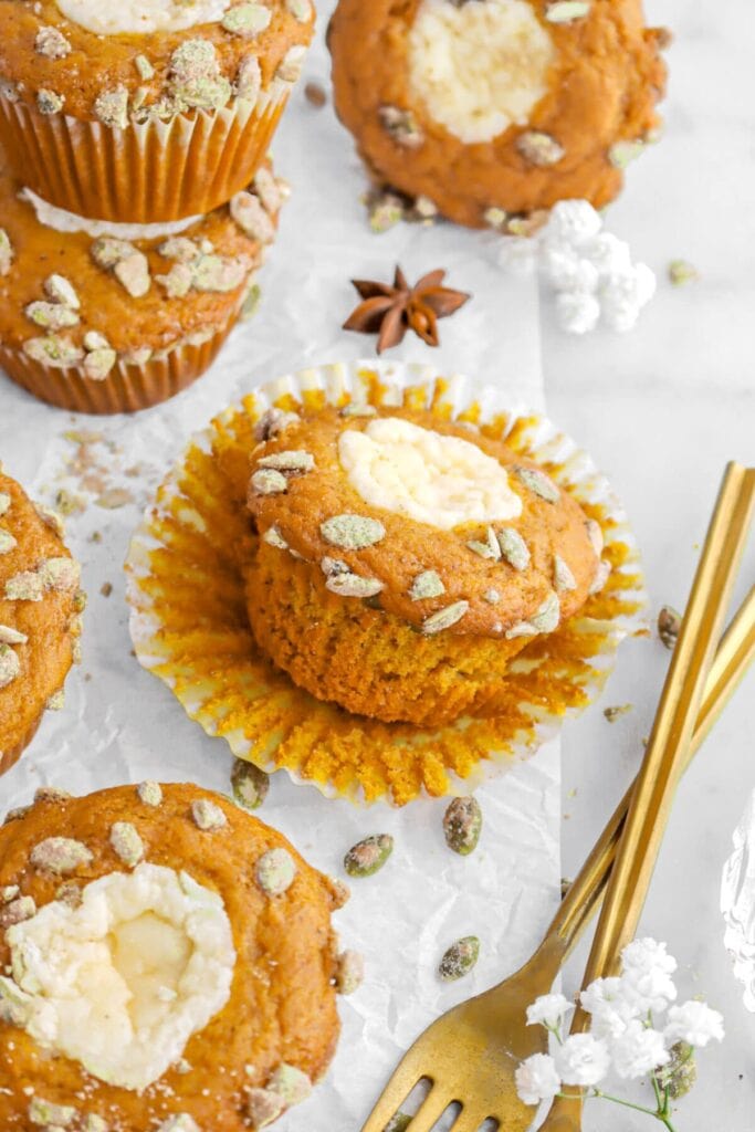 Spiced pumpkin muffins with sweet cream cheese filling on a parchment paper.
