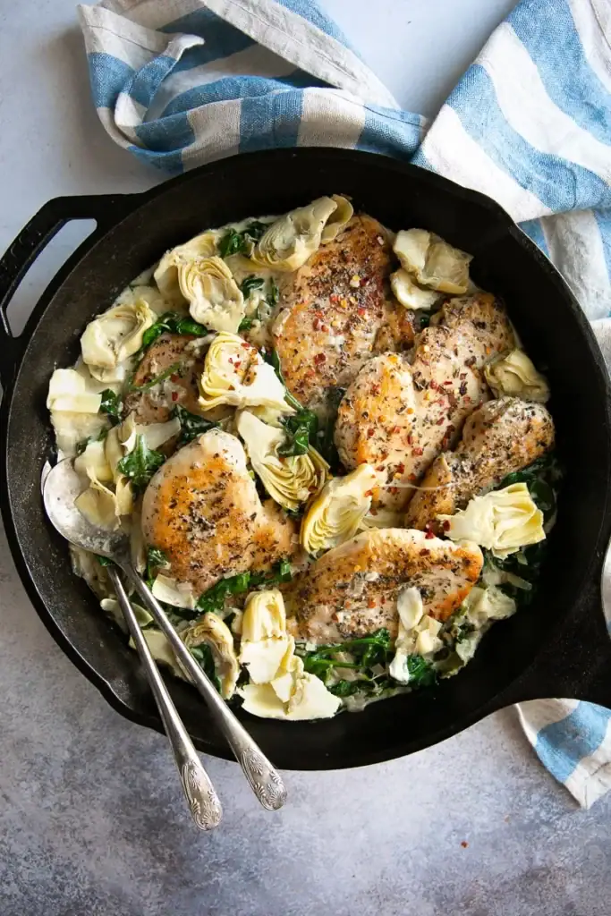 Spinach and artichoke chicken in a skillet.