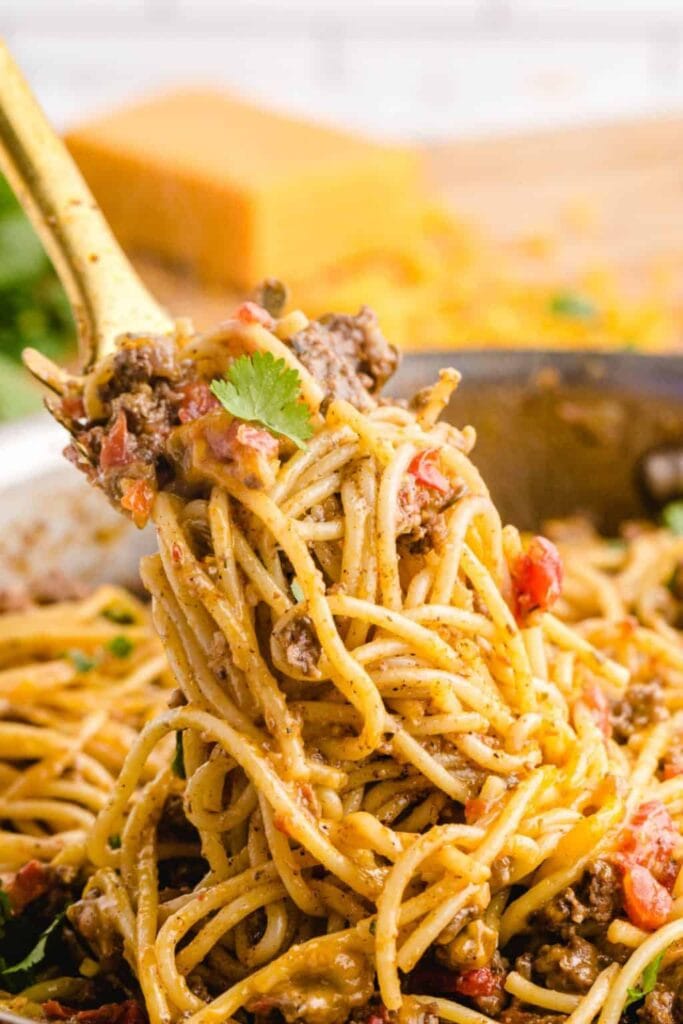 Taco spaghetti with ground beef being lifted from a skillet.