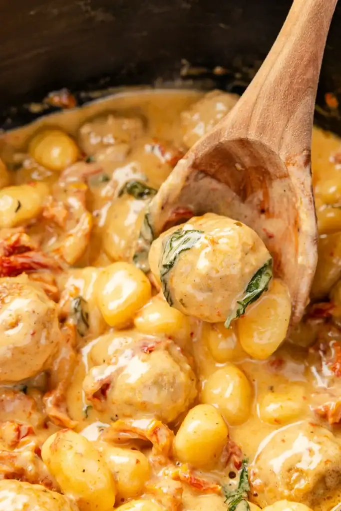 Close-up of Tuscan meatballs with gnocchi on a wooden spoon.