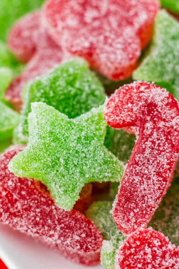 Close-up of red and green sugar-coated gummy stars and candy canes sparkling with crystals.