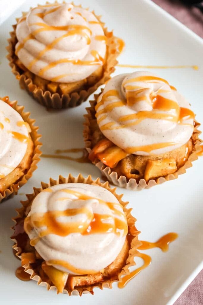 Apple cider cupcakes with cream cheese frosting on a plate.