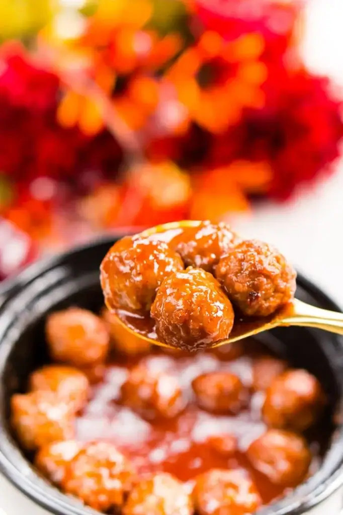 Close-up of apple cocktail meatballs on a spoon.