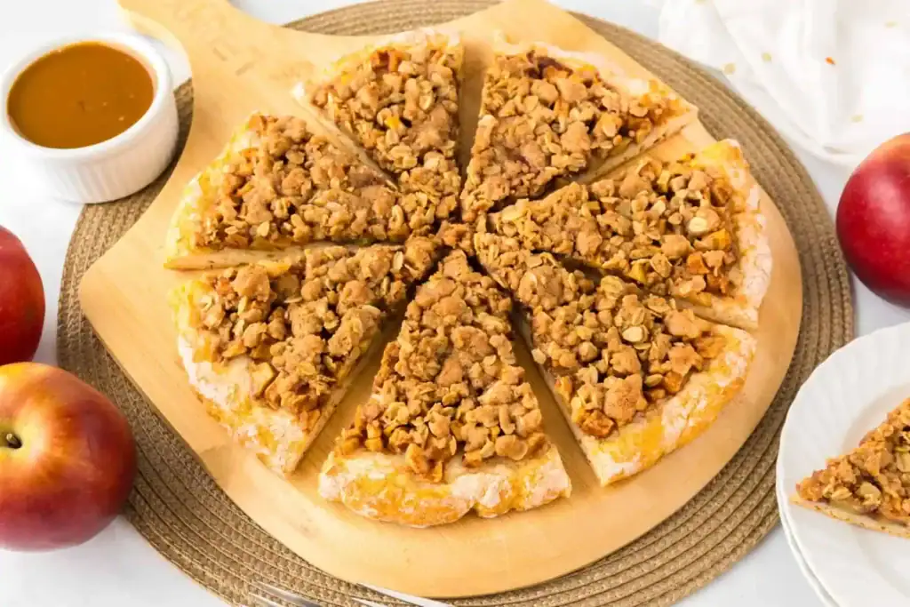 Apple dessert pizza on a wooden board.