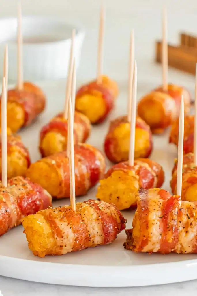 Bacon wrapped tater tots served on a plate.