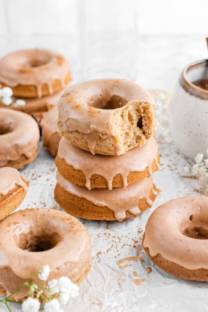 Baked apple cider donuts with spiced cider glaze on parchment paper.