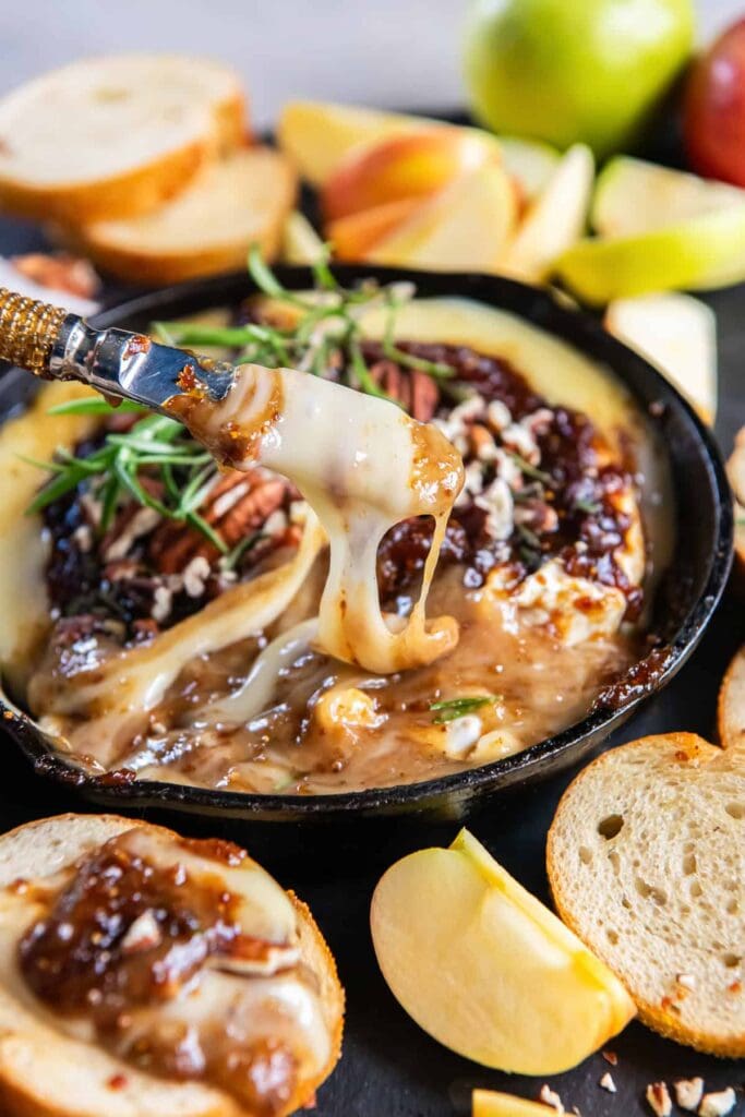 Close-up of baked brie with jam in a skillet.