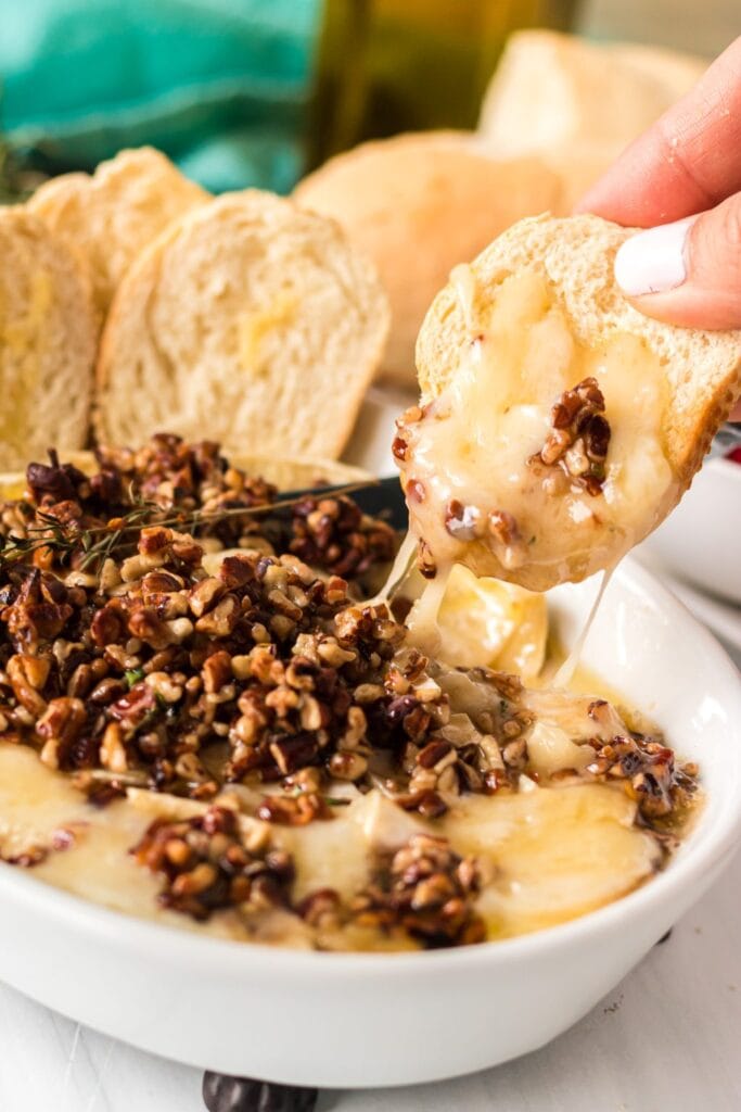 Close-up of baked brie with pecan honey topping in a baking dish.