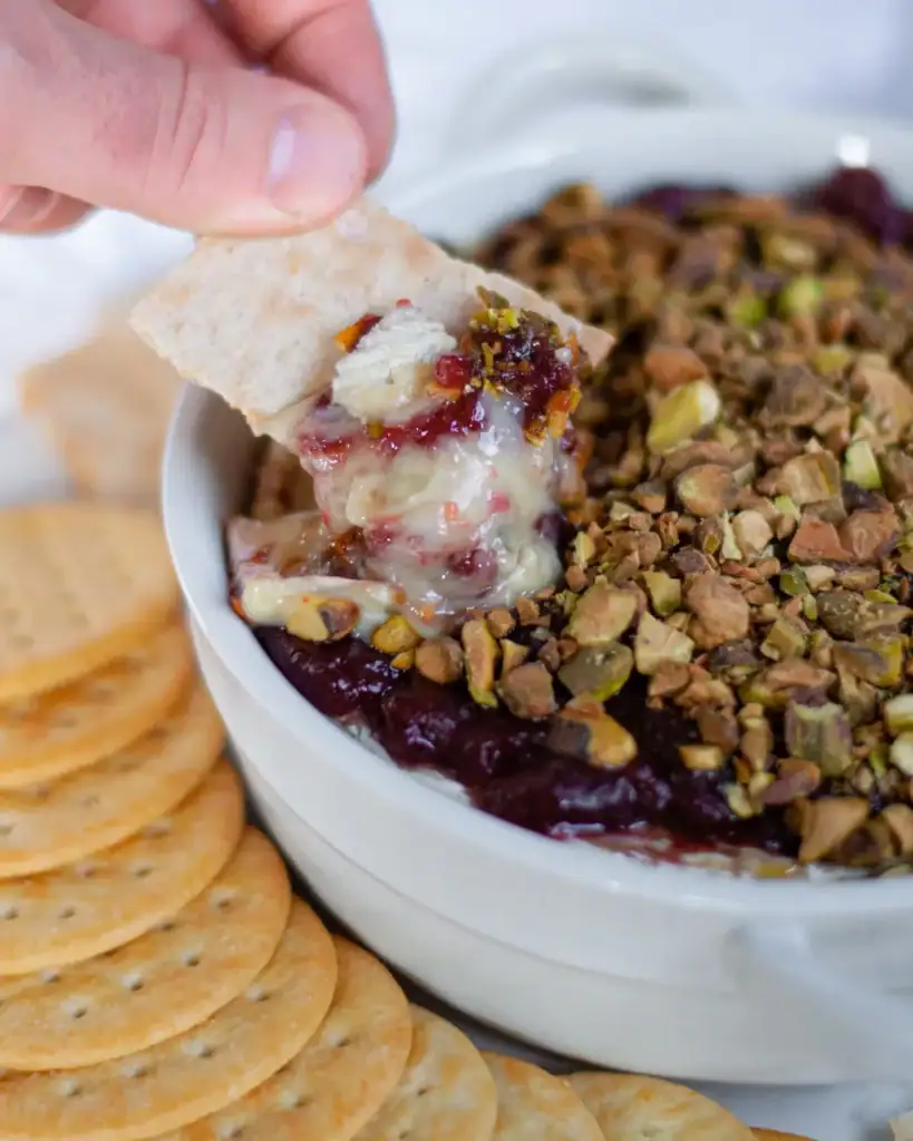 Baked brie with raspberry jam and pistachios in a bowl.