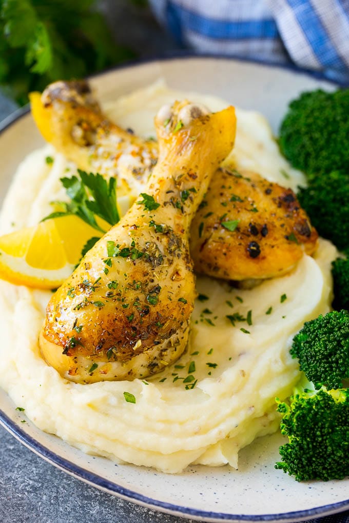 Baked chicken drumsticks served over creamy mashed potatoes on a plate.