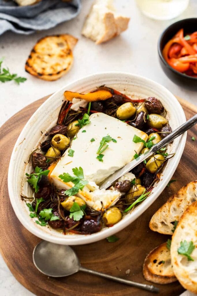 Baked feta with olives and rosemary served on a plate.