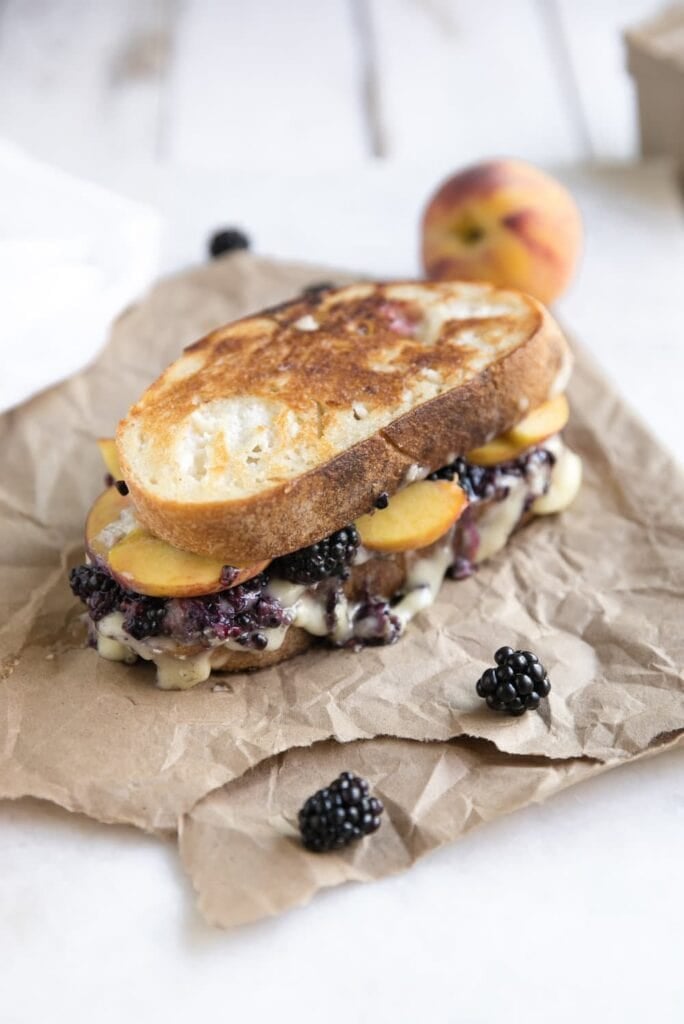 Blackberry and peach brie grilled cheese sandwich on parchment paper.