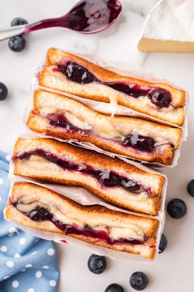 Stacked blueberry brie grilled cheese sandwiches with melted brie and blueberry filling.