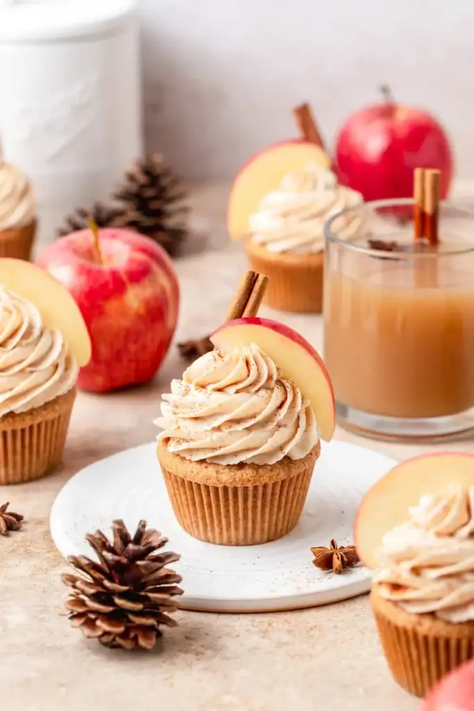 Brown butter apple cider cupcakes with frosting and apple slices.