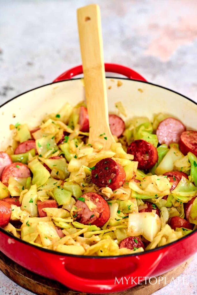 Cabbage and sausage cooked together in a skillet.