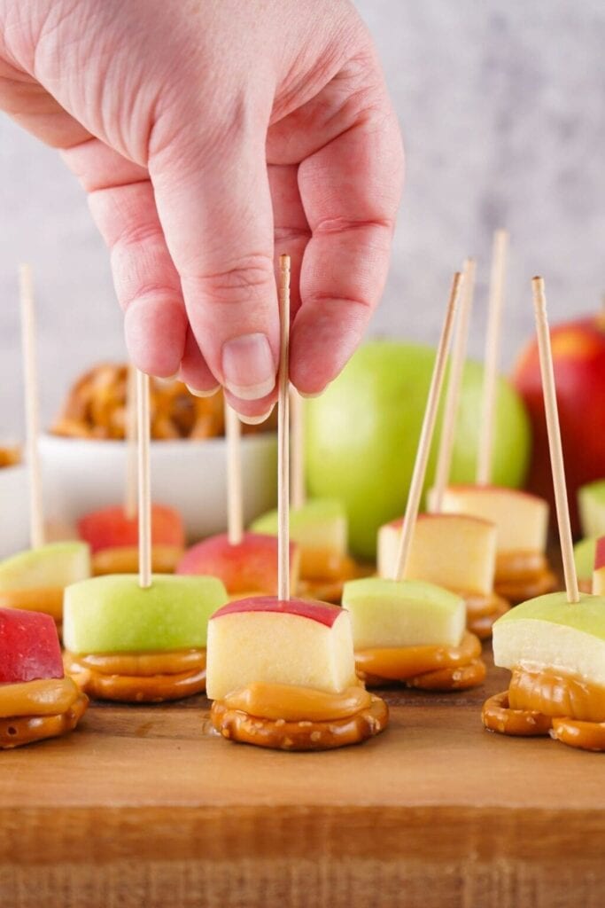 Caramel apple bites on a wooden board.