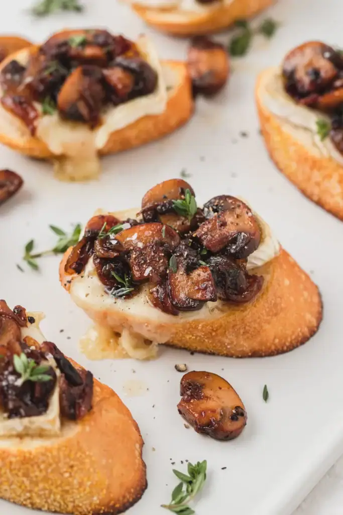 Close-up of caramelized mushroom and brie crostini on a plate.