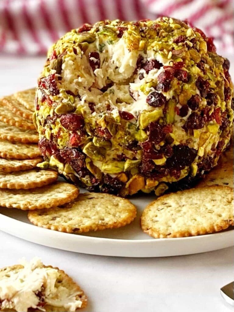 Cranberry brie cheese ball with crackers on a plate.