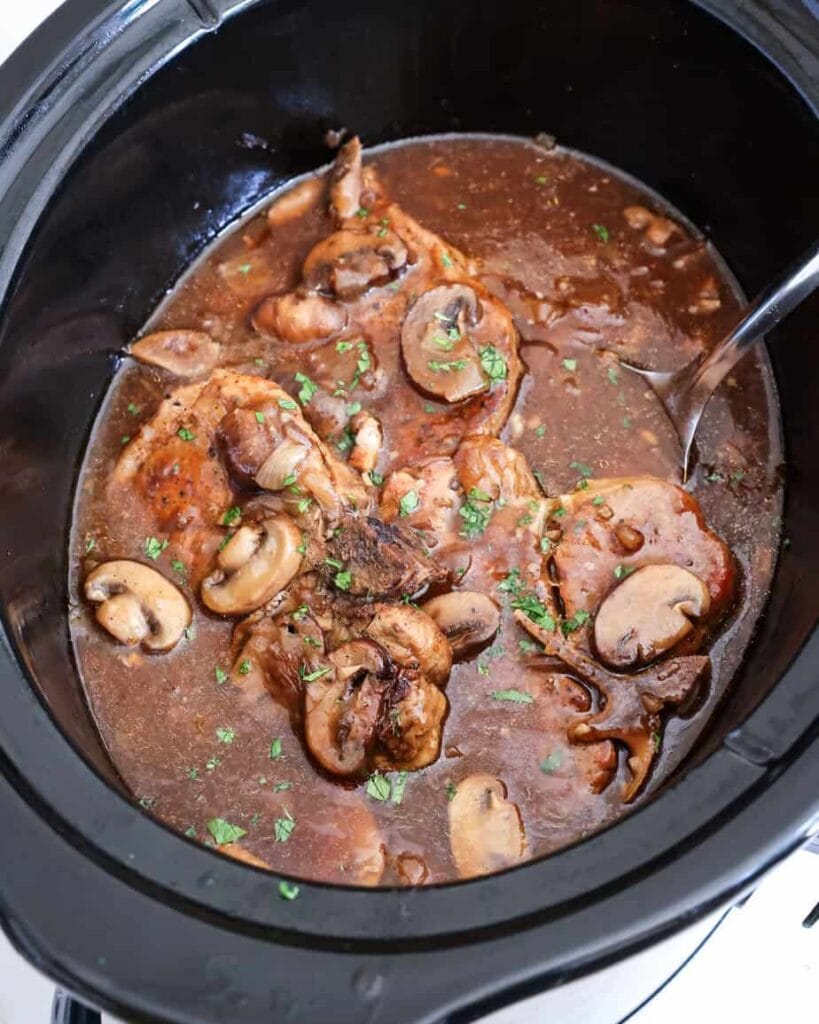Pork chops cooking in a crockpot.