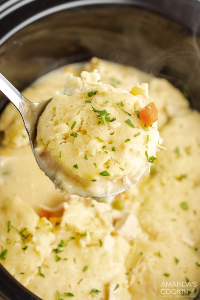 Crockpot chicken and dumplings on a serving spoon.