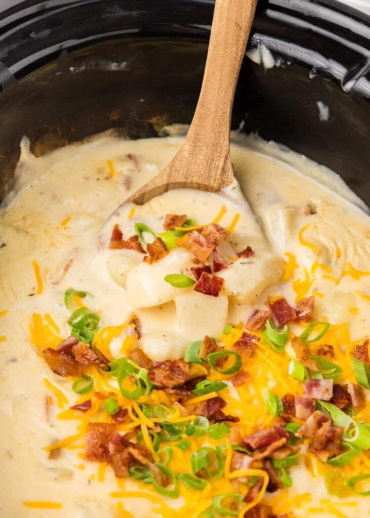 Crockpot potato soup on a wooden spoon.