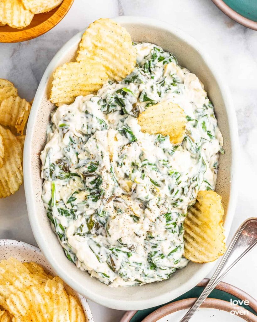 Crockpot spinach artichoke dip served with potato chips.