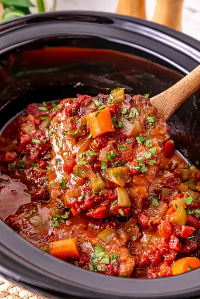 Serving spoon lifting crockpot Swiss steak.