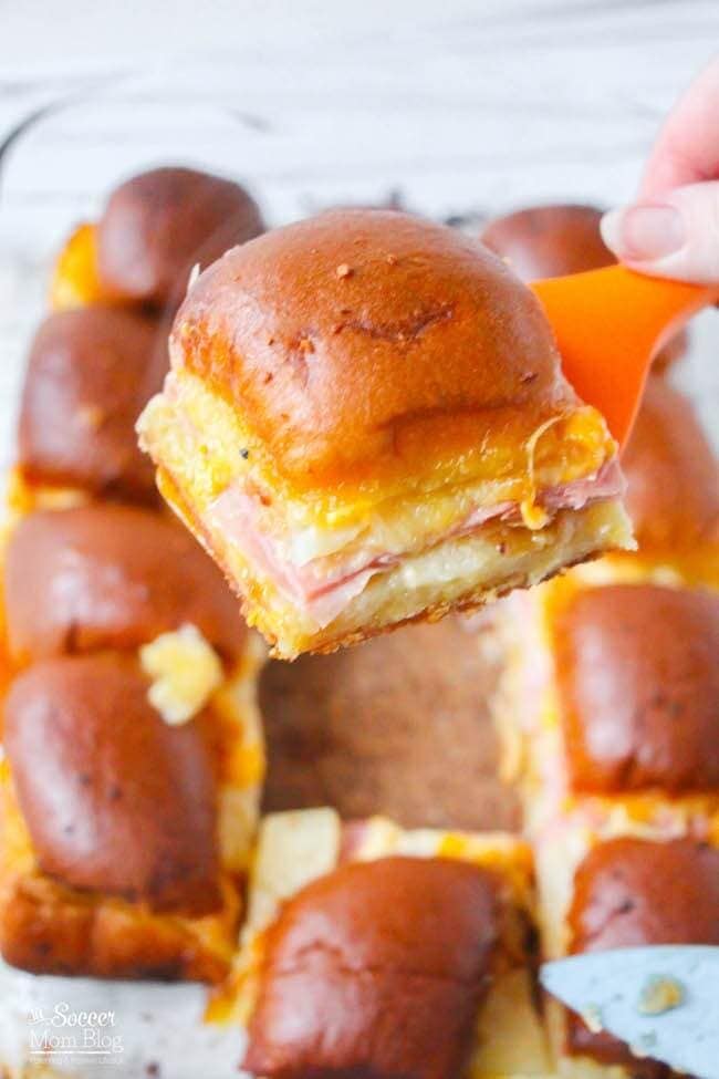 Close-up of a Hawaiian slider with ham and melted cheese on a spatula.