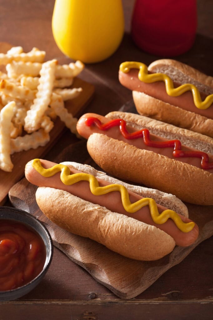 Hot dogs with mustard and ketchup on a wooden board.