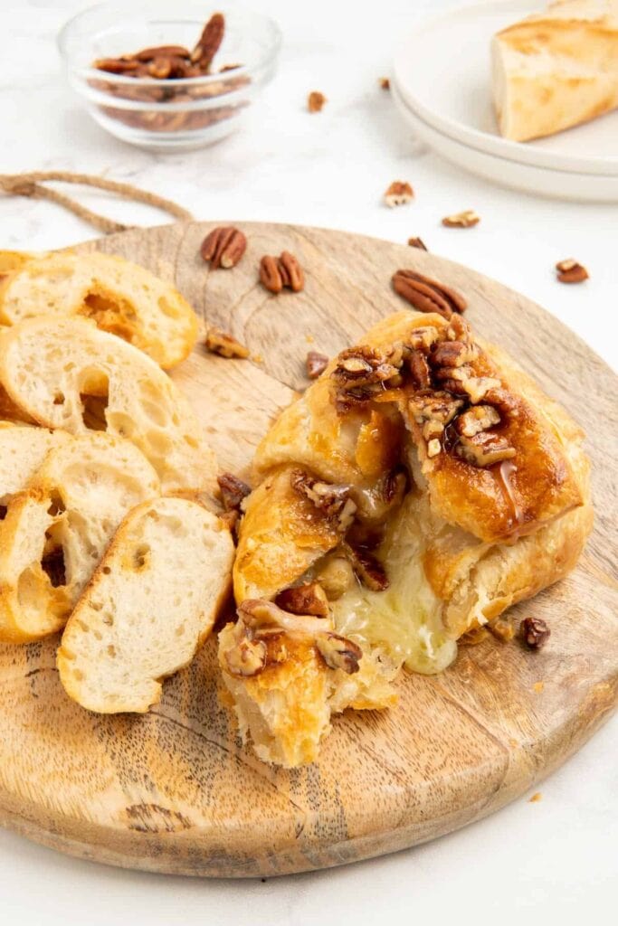 Maple pecan air fryer brie with sliced bread on a wooden board.