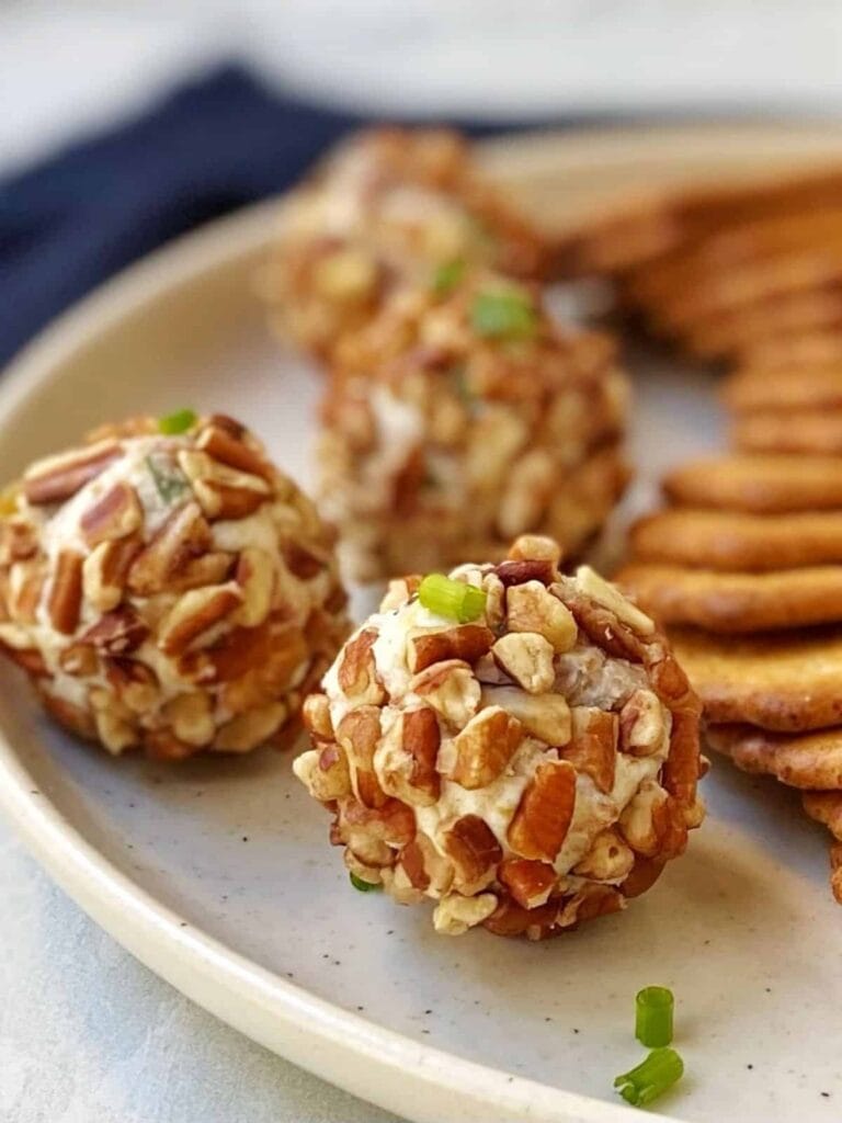 Mini cheese balls with fig and prosciutto on a plate.