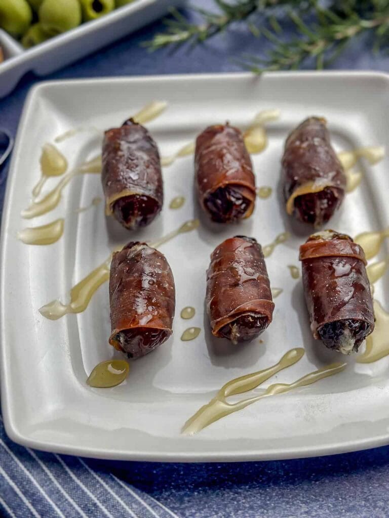 Prosciutto wrapped dates on a plate.