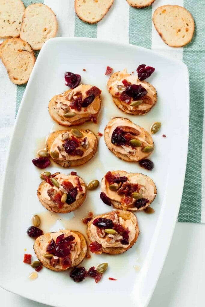 Pumpkin crostini with goat cheese and bacon on a plate.