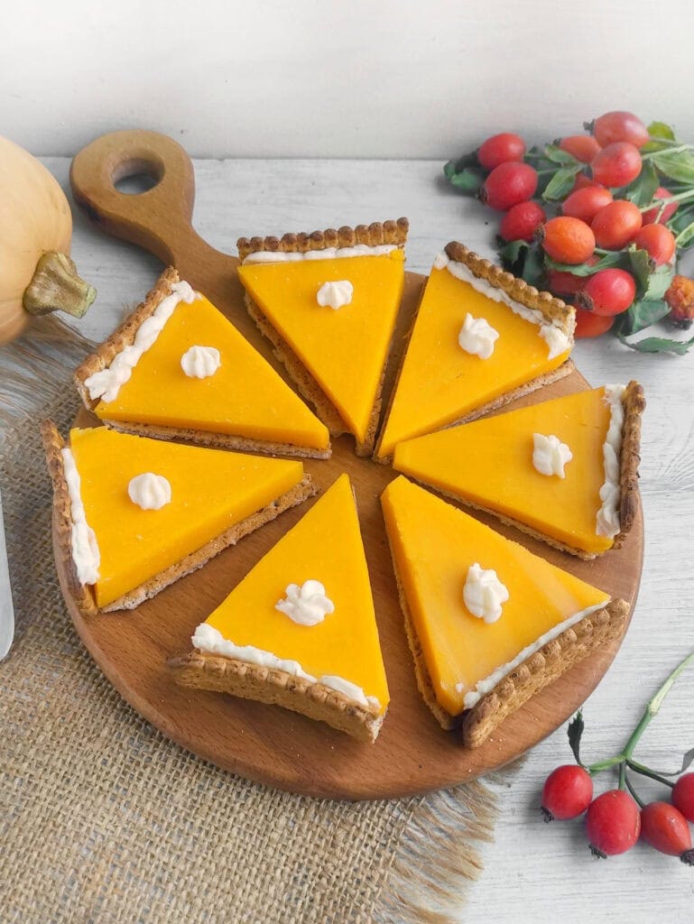 Slices of pumpkin pie cheese and crackers on a wooden board.