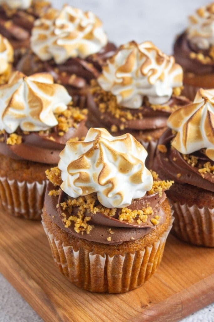 Pumpkin s’mores cupcakes on a wooden board.