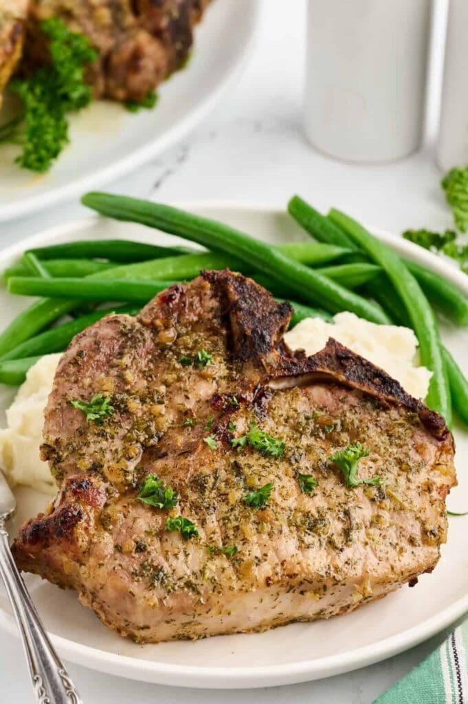 Ranch oven baked pork chops with green beans on a plate.