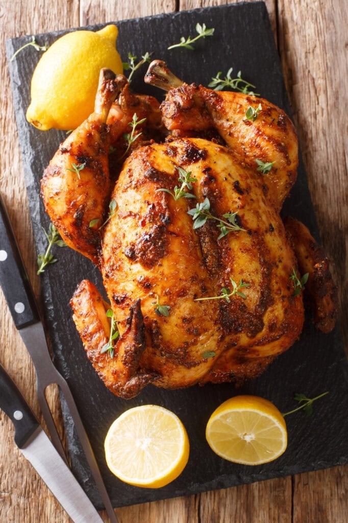 Rotisserie chicken on a slate board with lemon.