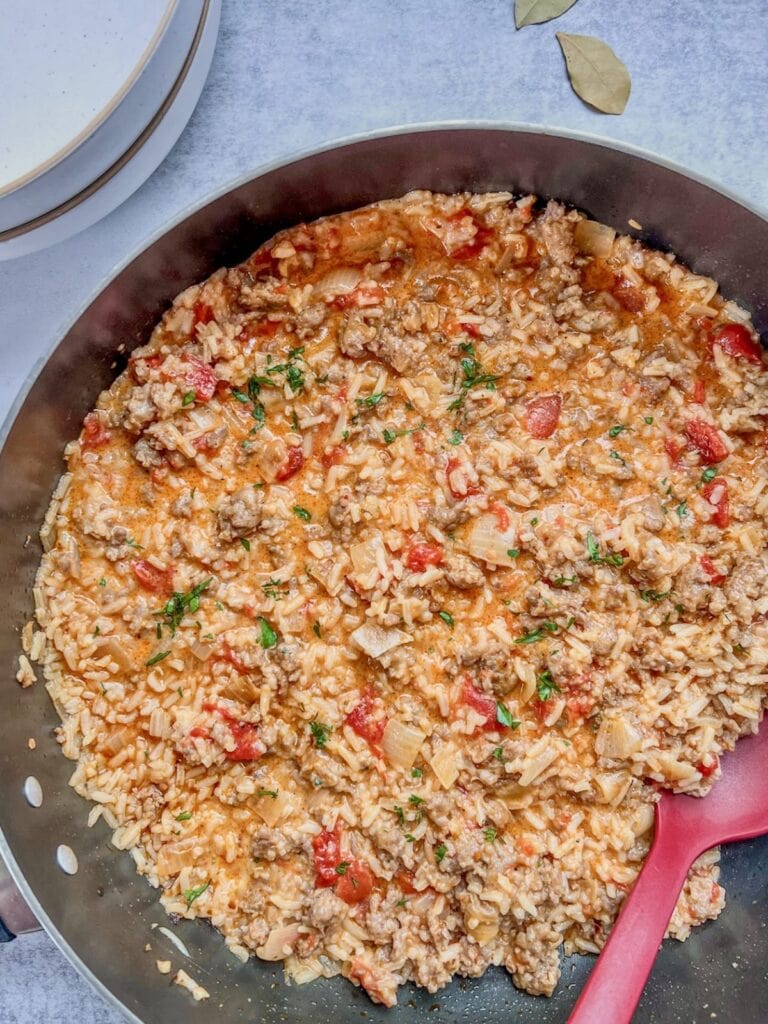 Sausage and tomato rice cooked together in a skillet.