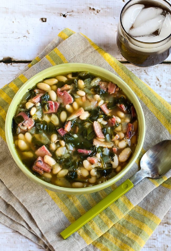 Slow cooker bean soup with ham and spinach served in a bowl.
