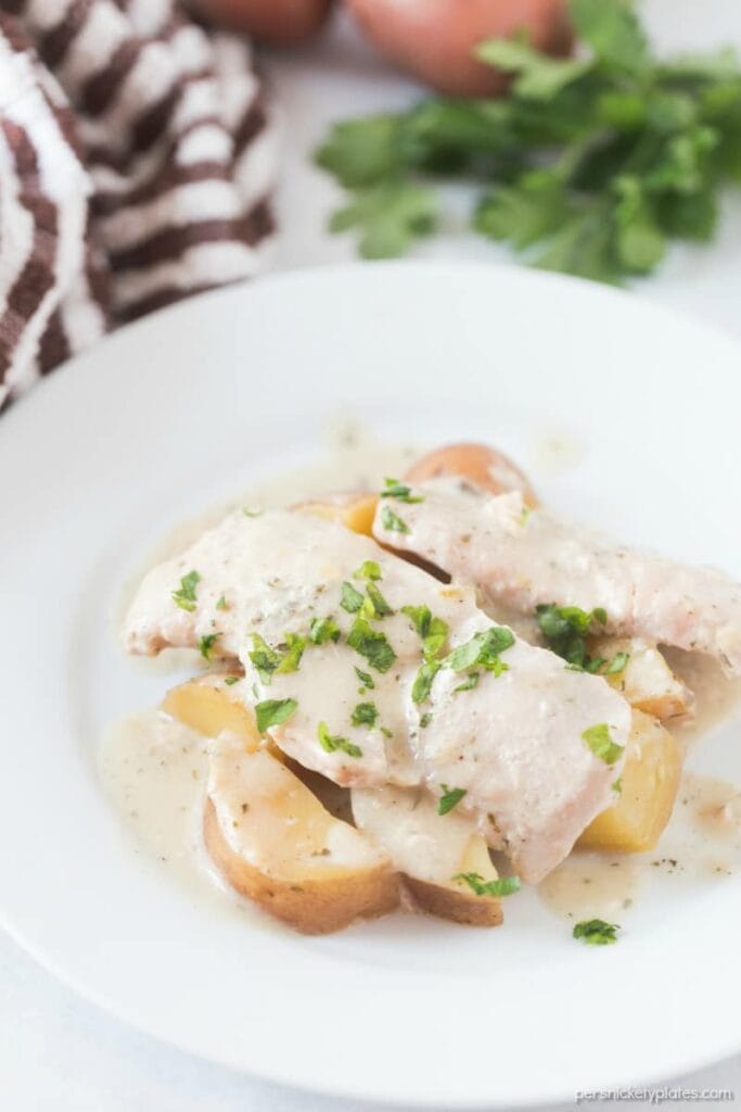 Slow cooker creamy ranch pork chops and potatoes served on a plate.