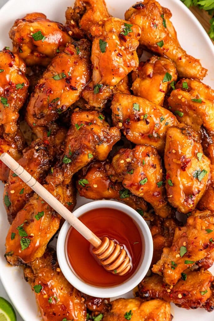 Slow cooker hot honey wings on a plate with honey dipping sauce.