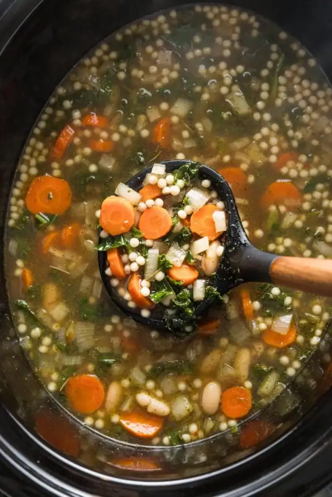 White bean soup with Parmesan and pearl couscous in a slow cooker.