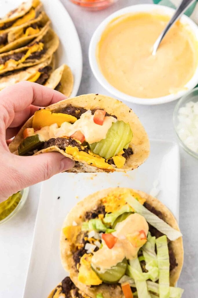 Close-up of smash burger tacos held in hand.