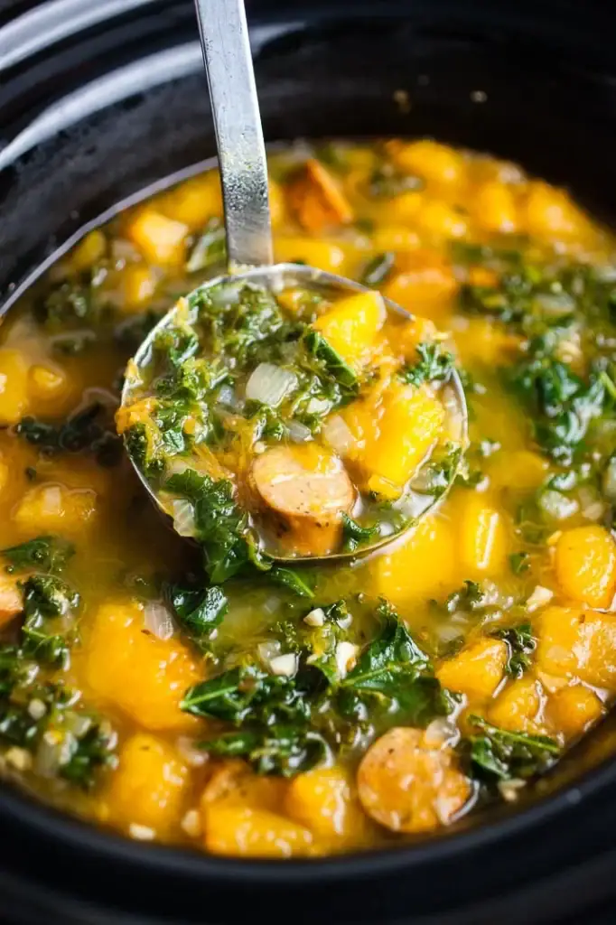 Squash, sausage, and kale soup on a ladle.