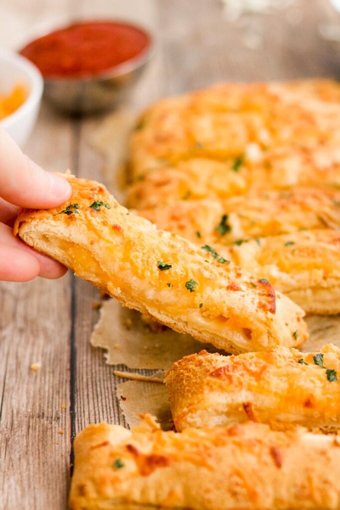 Close-up of a stuffed cheese breadstick held by hand.