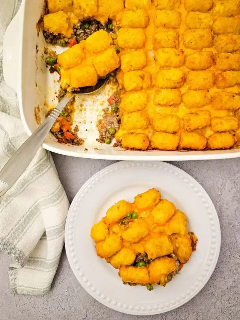 Tater tot casserole with ground beef served on a white plate.