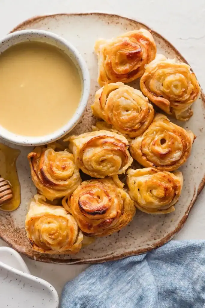 Turkey Gouda party rolls on a plate with dipping sauce.