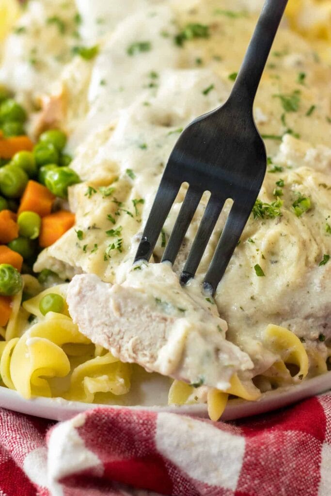 Oven baked pork chops with noodles and vegetables on a plate.