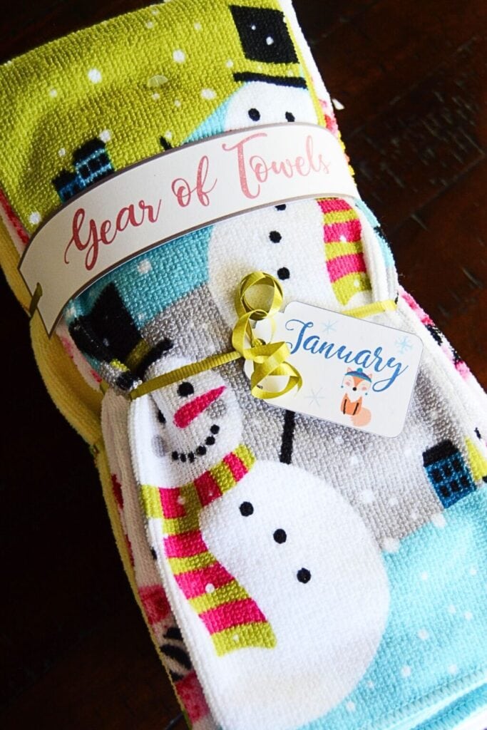 Folded snowman-themed towels bundled with “Year of Towels” band and January fox tag, tied with yellow ribbon.